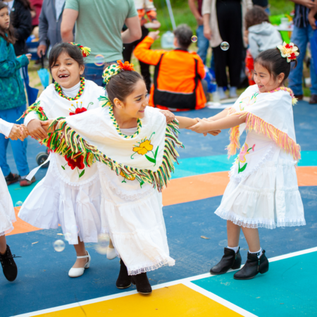 three young girls in white dresses dancing at hispanic heritage festival