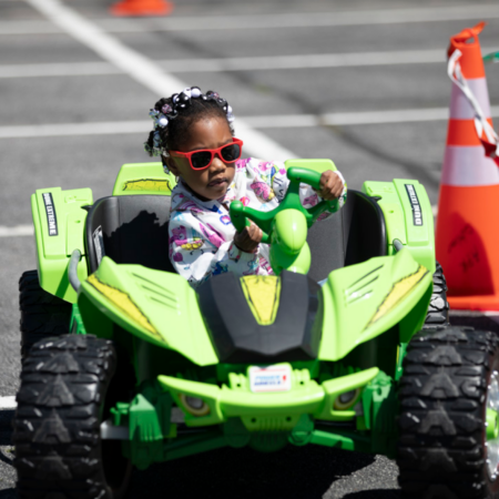 young african american girl in green toy jeep