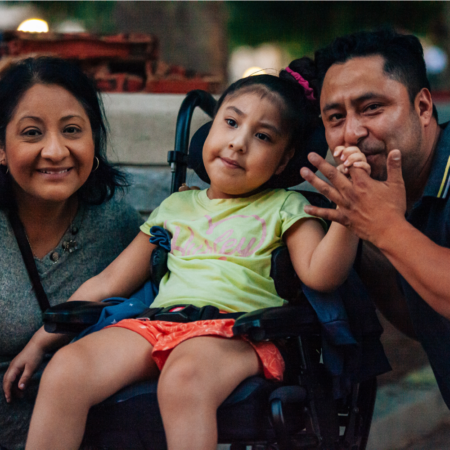 woman and man with young girl in a wheelchair at an event