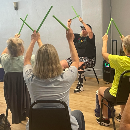 older adults sitting in chairs with drum sticks