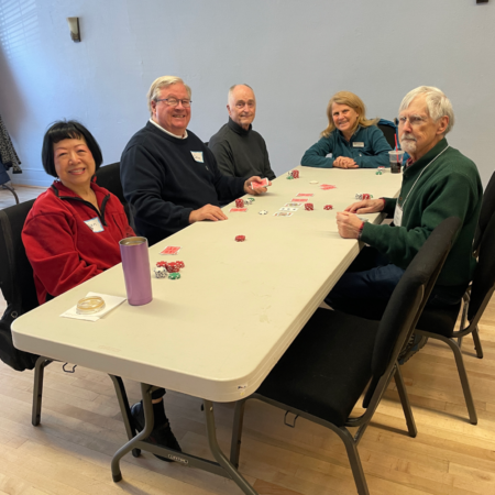group of 5 seniors playing poker at a table