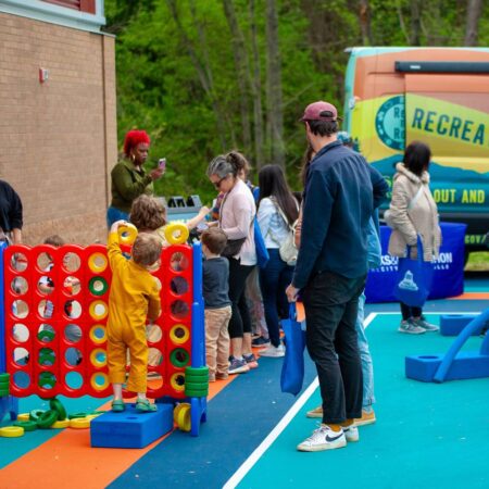 people playing with foam blocks and large connect 4 game beside rec and roll van