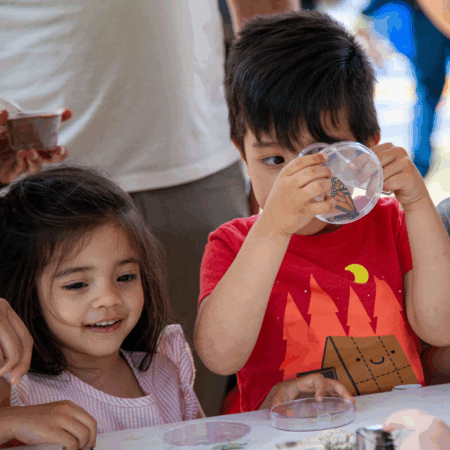 young boy holding magnifying glass beside young girl
