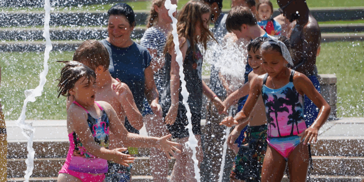 children in swimsuits playing at water splash pad