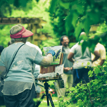 woman painting on an easel in the woods
