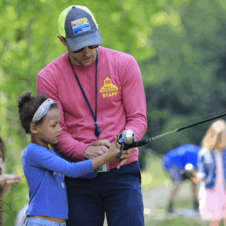 main and young child holding fishing pole by lake