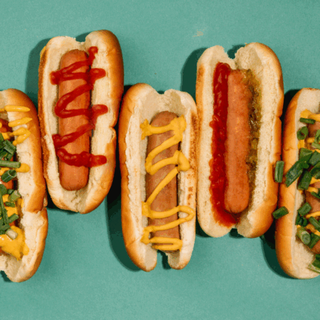hot dogs with ketchup, mustard and relish on blue background