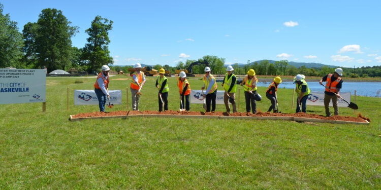 line of participants with shovels in various stages of "breaking ground" during the Mills River Treatment Plant ceremony