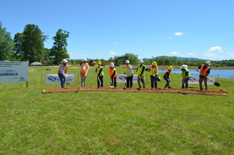line of participants with shovels in various stages of "breaking ground" during the Mills River Treatment Plant ceremony
