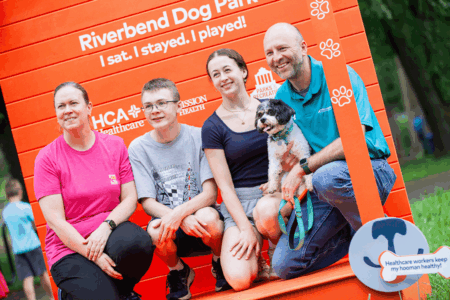 family of 4 with their dog in front of photo screen at dog park