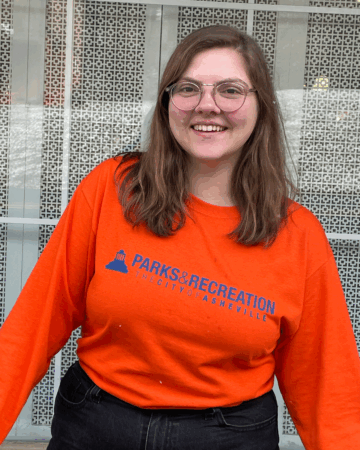 Rebecca Familette wearing orange Parks & Recreation shirt