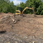 A trackhoe moves debris on site for the pilot program.