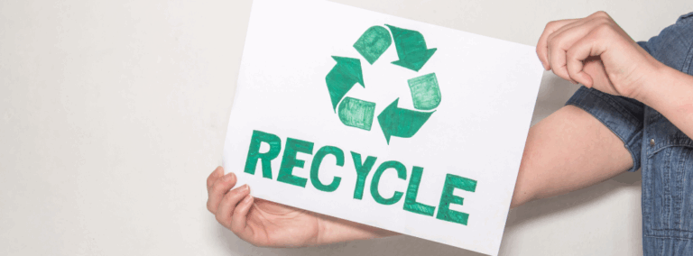 person holding a sign with a green recycle logo on it
