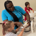 Anice Smith wearing blue shirt working with young girl in afterschool program