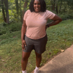 Anice Smith wearing pink Parks & Recreation shirt and dark gray shorts