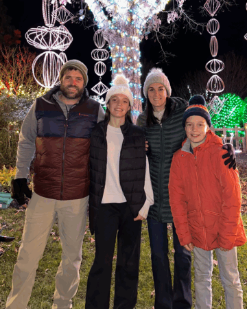 family of 4 in front of holiday lights