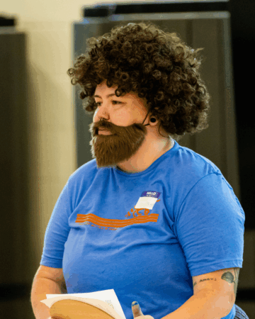 Fallon Hyder wears curly wig and fake mustache with beard
