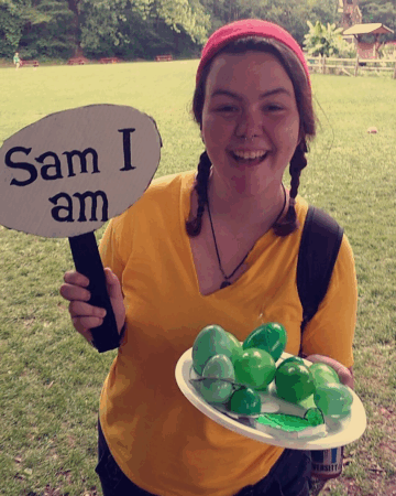 Fallon Hyder holds sign that says 'Sam I Am' while holding a tray of green eggs