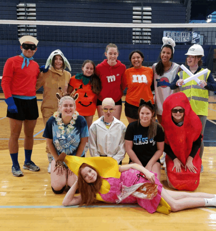 volleyball team wearing halloween costumes in front of net