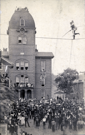 A large crowd gathered to watch two men on a high wire in front of the Buncombe County Courthouse, circa 1887