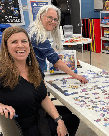 two women put together a puzzle at a table