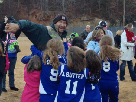 Dwayne Walker surrounded by young girls in blue athletic uniforms