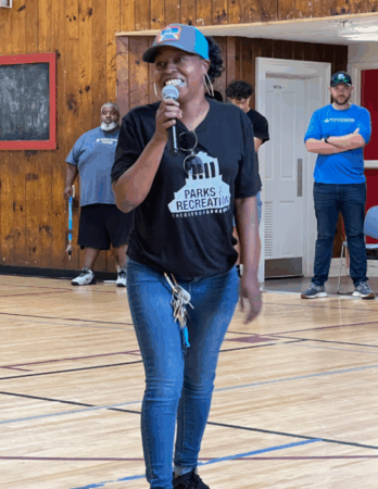 Christin King speaks with microphone in gymnasium