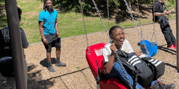 APR team member and kids on a playground swing set