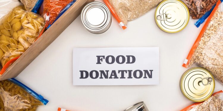 bags of pasta and rice and canned goods surround a white sign that says food donation
