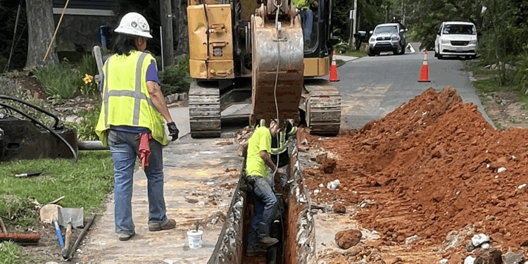 staff work in ditchline in the road to repair a waterline