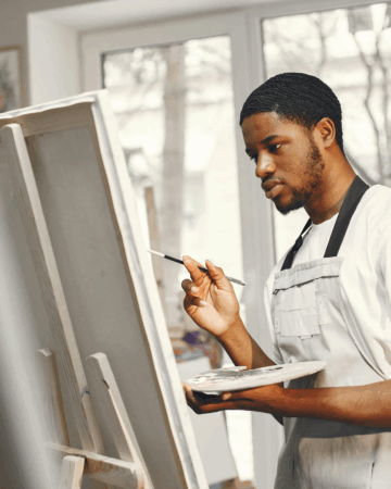 a man uses paints on a tabletop canvas