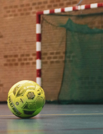 Futsal ball on gym floor in front of a goal