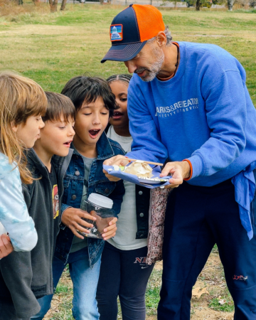 adult showing insects on a plate to amazed children