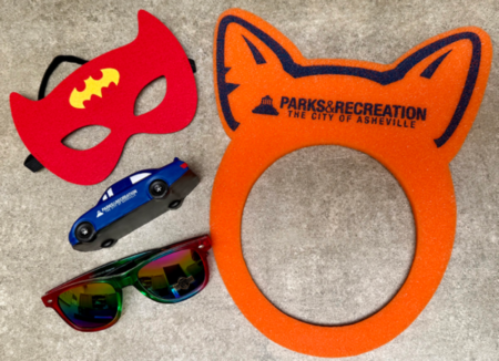 display of promotional items including superhero mask, foam car, sunglasses, and animal ear visor