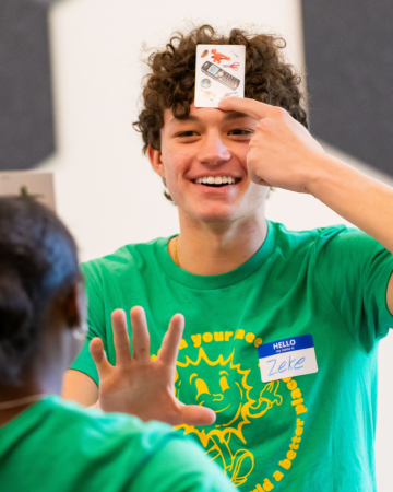  teen playing a game with a card pressed to his head