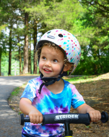 kid on strider bike wearing a tie dye shirt