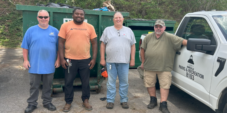 Will Ray and three other Asheville Parks & Recreation employees in front of a dumpster