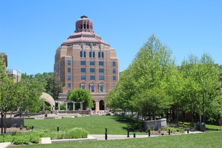 City ha;; on a sunny summer day with blue skies over City hall and lush green park and trees surrounding it