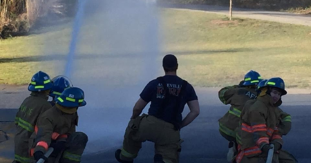 explorer participants with personal protective gear on holding hose with water spewing out