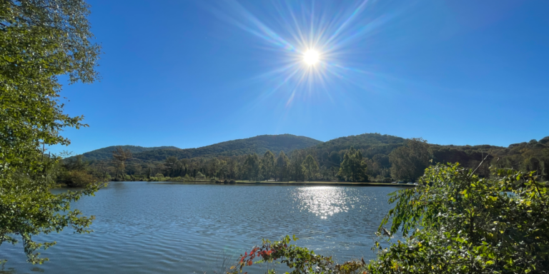 panoramic view of azalea pond with mountains and sun in background